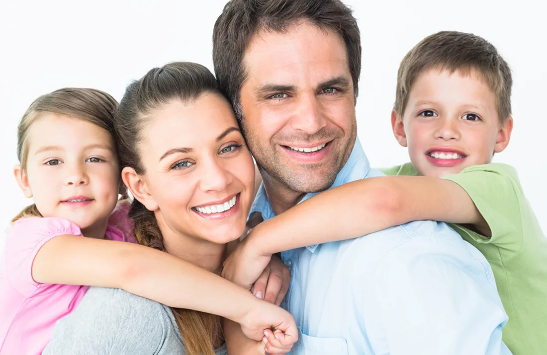 A family of four together, all smiling